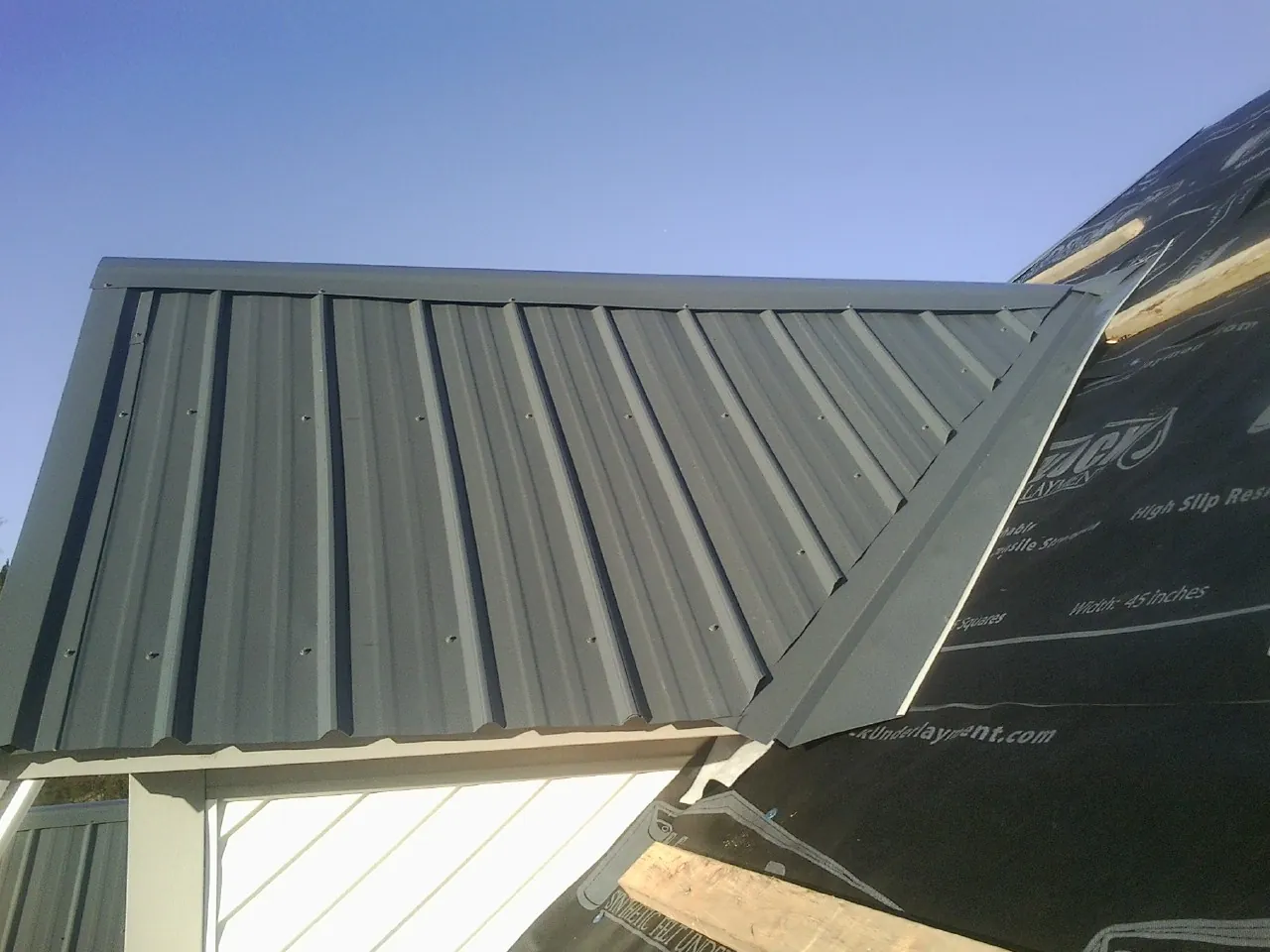 Gray metal roof panels going on over a garage gable in Bow