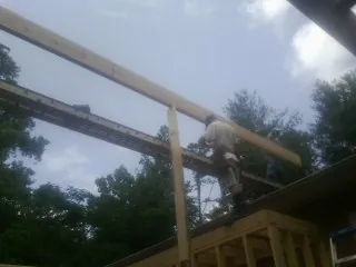 Carpenter setting a ridge beam over a new addition frame — Ice Dam Removal by Roofing Brothers in Bow
