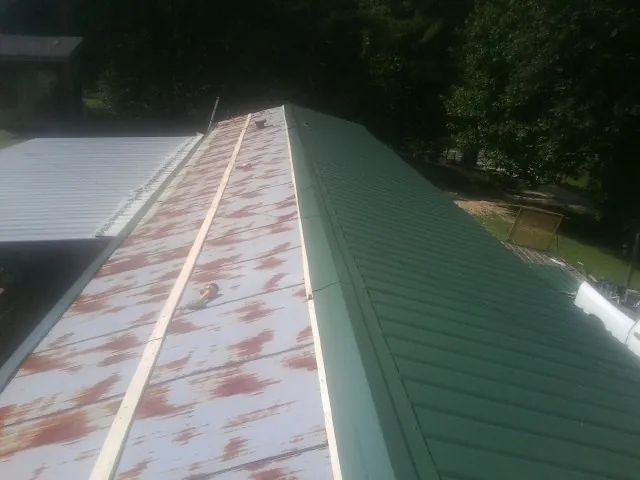 Old rusted panels beside newly installed green metal roofing — Wind Damage Roof Repair by Roofing Brothers in Bow