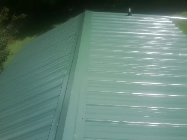 New green metal panels meeting at the ridge of a roof — Flat Roof Repair work by our crew in Bow