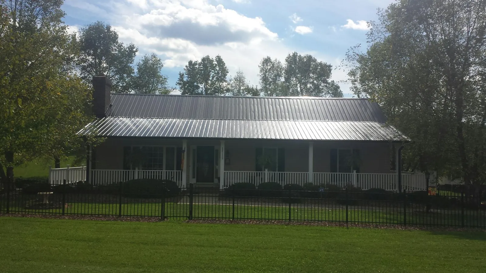 Gray metal roof on a brick ranch with a full width front porch — Gutter Guard Installation work by our crew in Bow