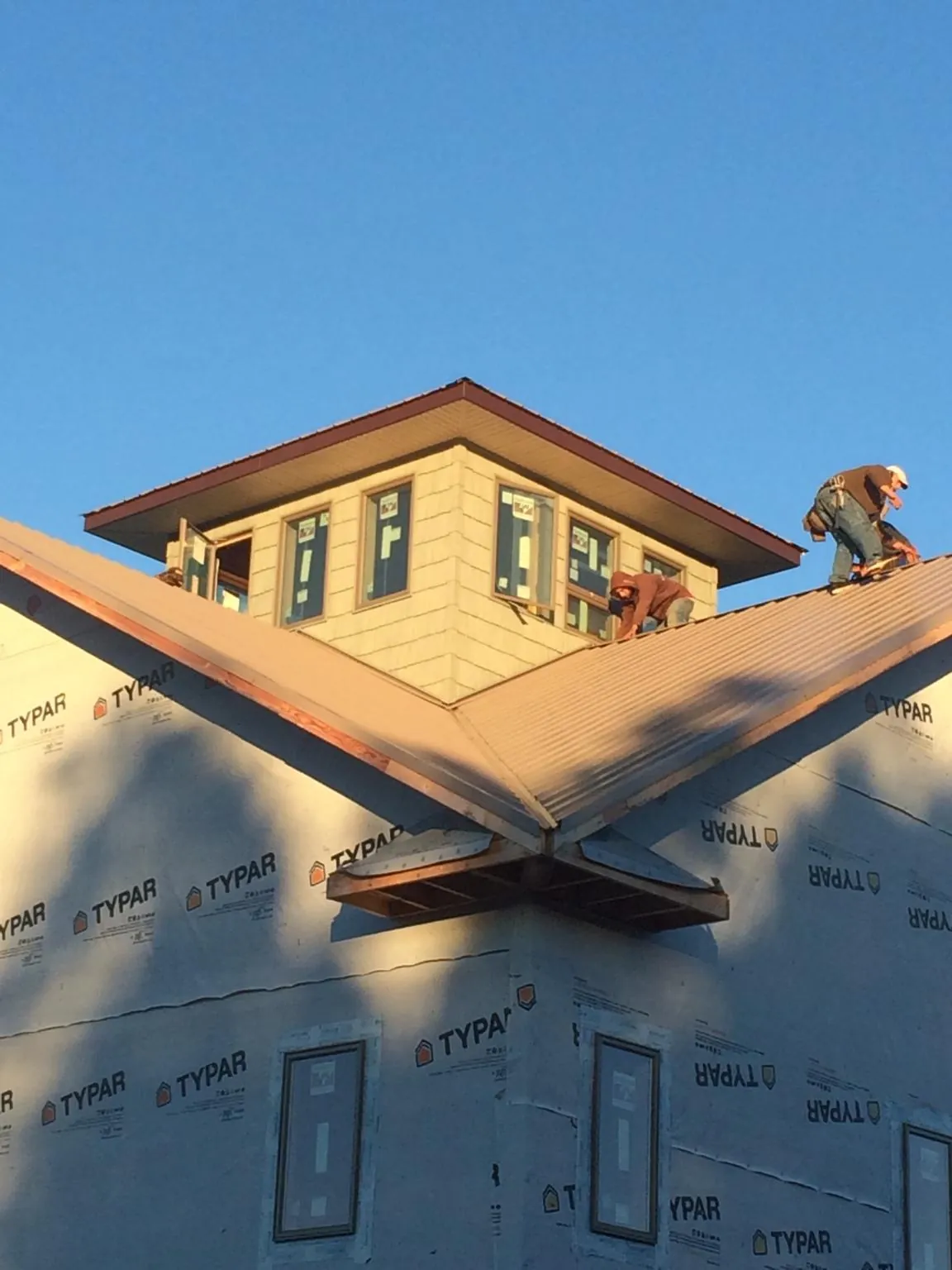 Roofers working around a rooftop cupola on a new metal roof at sunset — Roof Waterproofing in Bow by Roofing Brothers